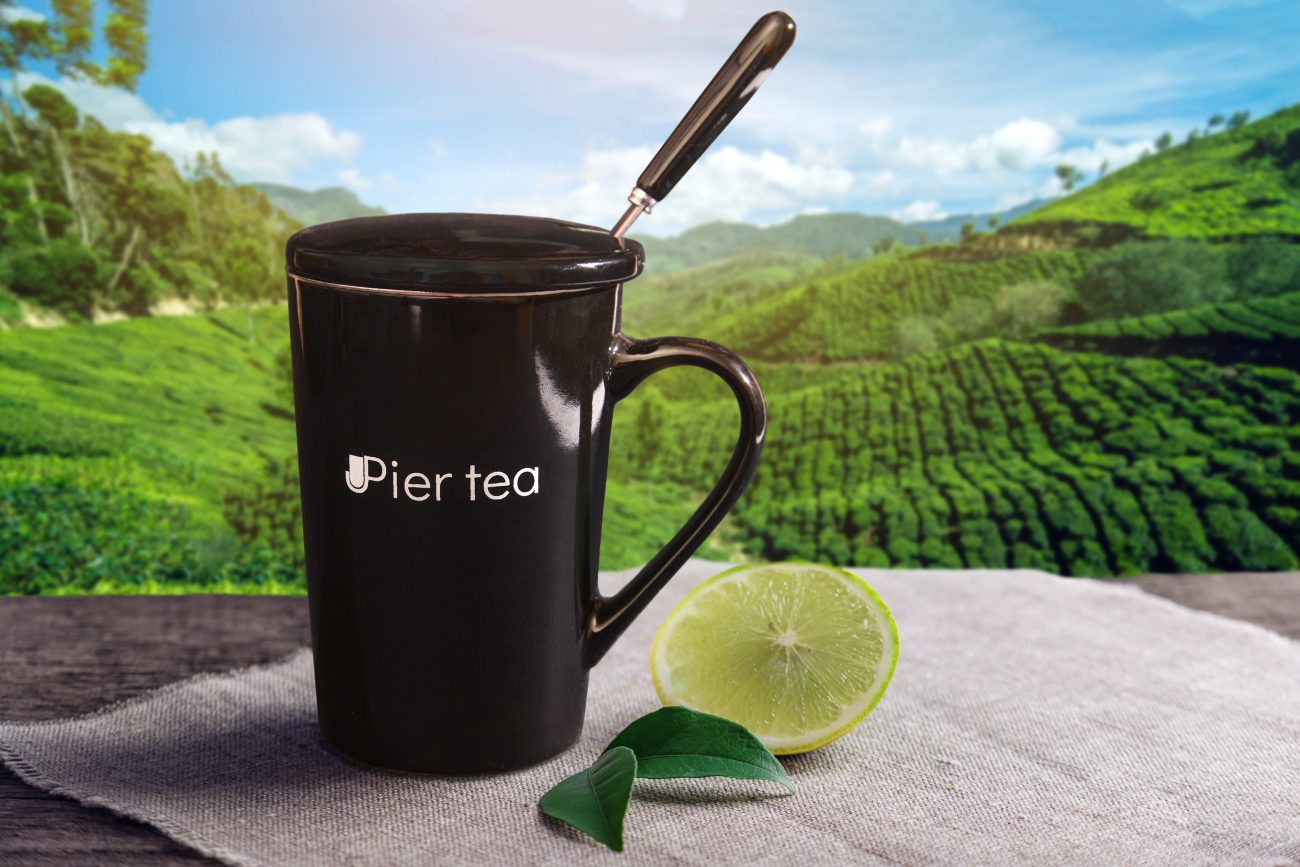 Cup of hot brown tea with a piece of lemon on the table on the background of plantations. Concept tea beverage industry